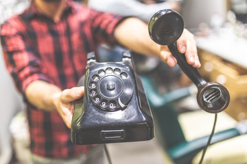 Close up of fashionable man hands holding vintage landline telephone.