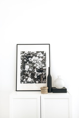 Photo frame on chest of drawers with decoration at white wall. Minimal modern Scandinavian nordic interior design concept.