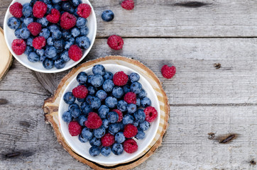 Still life with a blueberries and raspberries on an old wooden table, at the garden. Rural natural food style.