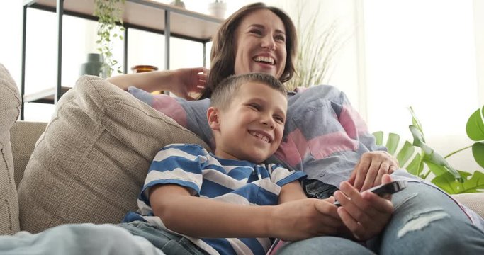 Relaxed mother and son laughing while watching comedy on tv