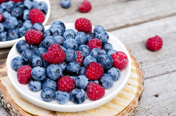 Still life with a blueberries and raspberries on an old wooden table, at the garden. Rural natural food style.