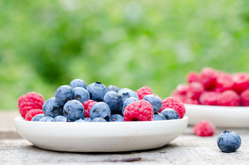 Still life with a blueberries and raspberries on an old wooden table, at the garden. Rural natural food style.