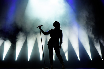 Vocalist singing to microphone. Singer in silhouette - obrazy, fototapety, plakaty