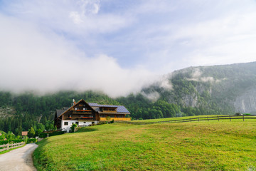 Plakat Morning in the Alps. Beautiful foggy morning scenery in Alps region, Austria. Great morning view of foggy mountains, fog, house and green meadow in Austria