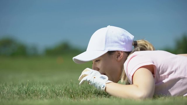 Cunning woman hitting golf ball in hole with finger, having fun during game