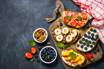 Sweet toast assortment with fresh fruit and berries on black.