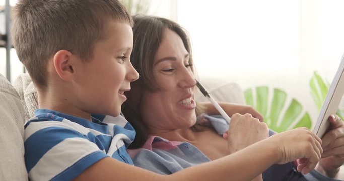 Mother and son having fun while making shopping list in notepad at home