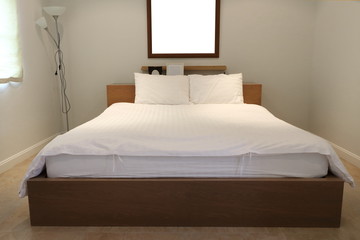 Plain bedroom interior, white pillows and mattress use white linen on wooden bed