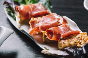 Pincho omelette and ham, with olives. In a restaurant