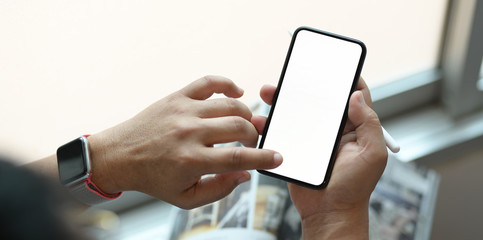 Cropped view of man using his blank screen smartphone