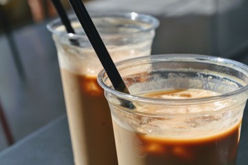 Close up view of ice coffees in glasses with straws. Cold brewed coffee with milk in plastic...