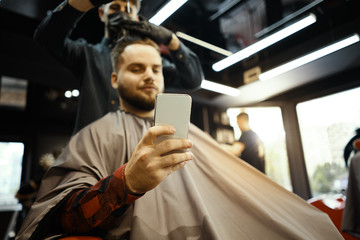 a guy doing a haircut and styling a beard 