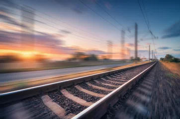 Foto op Plexiglas Treinspoor Spoorweg en mooie blauwe lucht met wolken bij zonsondergang met bewegingsonscherpte effect in de zomer. Industrieel landschap met treinstation en onscherpe achtergrond. Spoorwegplatform in snelheidsbeweging. Concept