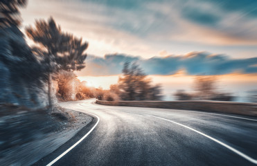 Mountain road at sunset with motion blur effect.  Asphalt road and blurred background with rocks,...