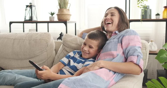 Mother and son having fun while watching comedy on tv at home