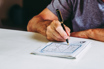 Mains d'un homme en train de faire un jeu de sudoku