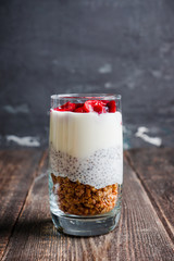 Plain yogurt with chia seed, muesli and cherries in glass on the rustic wooden background. Selective focus. 