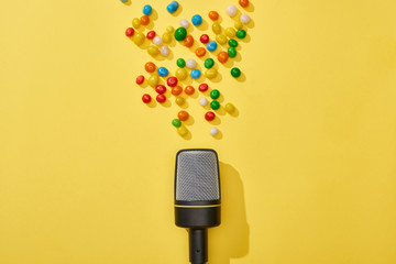 top view of microphone and candies on bright and colorful background