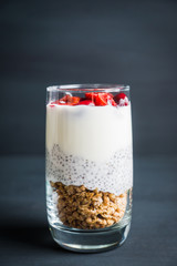 Plain yogurt with chia seed, muesli and cherries in glass on the rustic wooden background. Selective focus. 