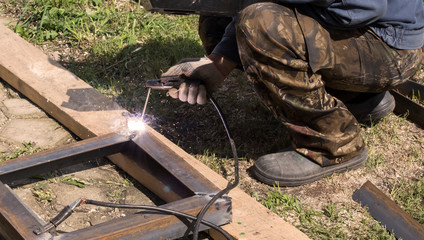professional welder welds metal parts by electric welding