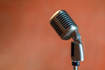 Fototapeta na wymiar Retro vintage metal stainless steel microphone on stage isolated on orange background.