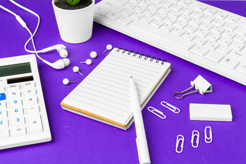 Composition of office lifestyle items on  purple background, computer keyboard office supplies on desk in office