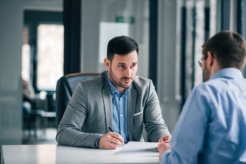 Handsome businessman having pensive look, feeling doubtful about signing contract.