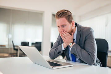 Naklejka premium Redhead businessman looking at laptop screen in shock at the off