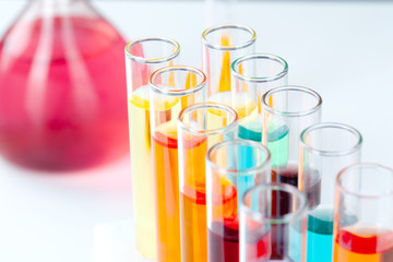 Colored liquids inside lab glassware on white table in laboratory