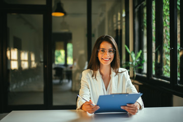 Portrait of a young positive female job applicant holding document