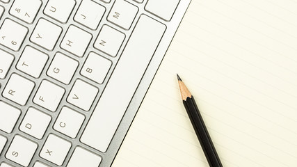 modern white office desk with a computer keyboard, pen, and a notebook. - top view with copy space.