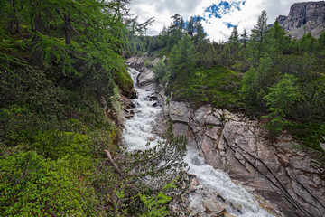 Obraz premium Panoramic view of the rushing waters of a stream in the Swiss Alps.
