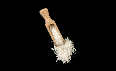 coconut shreds in wooden scoop isolated on black background. top view. spices and food ingredients.