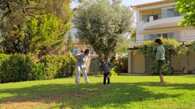 Grandmother daughter and grandson doing morning exercises. Body care concept. Women of different ages doing sports with child on green grass in the summer. Vacation near the sea