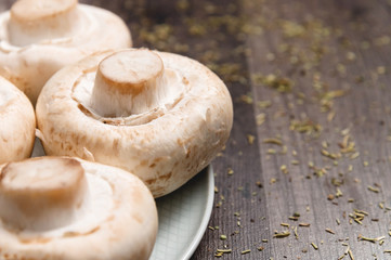 Close-up of white mushrooms on a white plate on a dark wooden table. Vegetarian healthy food