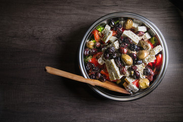 Close-up of delicious gourmet tomato and olives feta cheese salad sprinkled with herbs spices in a metal bowl. The concept of delicious and healthy vegetarian food and body detoxification