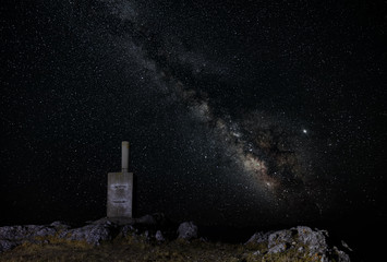 Fototapeta na wymiar At the top of Monte Ardal mountain near the Spanish city of Yeste. It is night and the Milky Way is visible in the sky. A stone block marks the summit point.