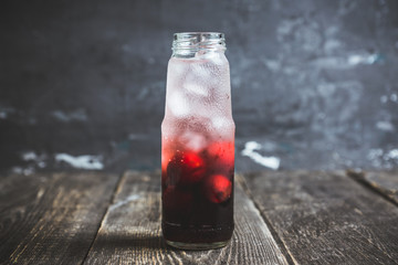 Cherry drink with berries and ice in small bottle. Selective focus. Shallow depth of field.