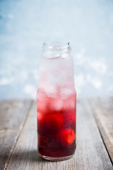 Cherry drink with berries and ice in small bottle. Selective focus. Shallow depth of field.