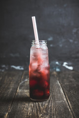 Cherry drink with berries and ice in small bottle. Selective focus. Shallow depth of field.