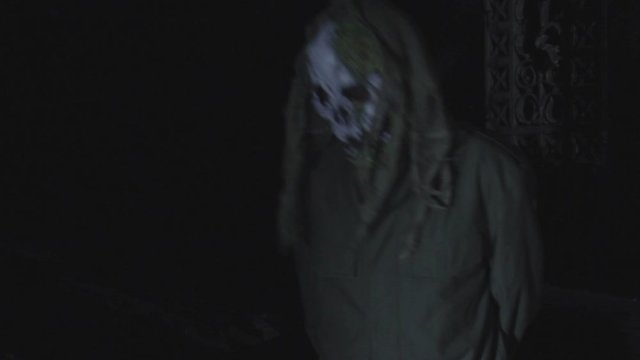Unrecognizable man with scary halloween mask at night in the dark. Black magic ritual or scary halloween party performance