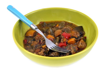 Assiette de ratatouille avec une fourchette  sur fond blanc