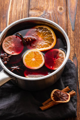 Mulled wine hot drink with citrus, apple and spices in aluminum casserole and Fir branch on background.