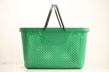 Green plastic shopping basket with black handles.