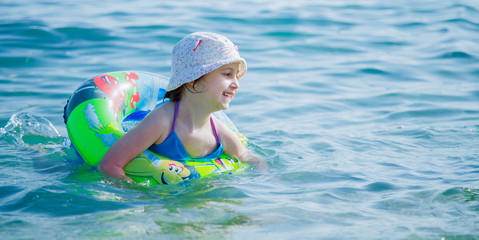 Fototapeta na wymiar Smile as the biggest indicator of a kid’s happiness. Cute little child girl having fun in water. Summer vacation and healthy lifestyle concept