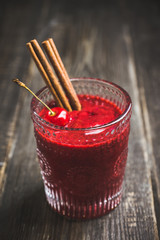 Cherry smoothie with cinnamon in old fashioned glass on the rustic wooden background. Selective focus. Shallow depth of field.