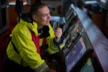 Navigator. pilot, captain as pat of ship crew performing daily duties with VHF radio, binoculars on...