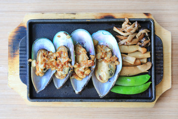 Baked mussels served with vegetables on plate. Japanese seafood.