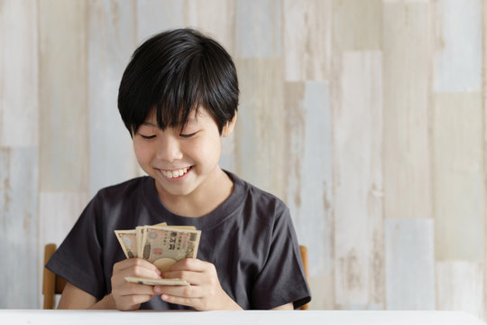 1万円札を数える小学生の男の子