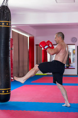 Muay thai fighter hitting the heavy bag in the gym